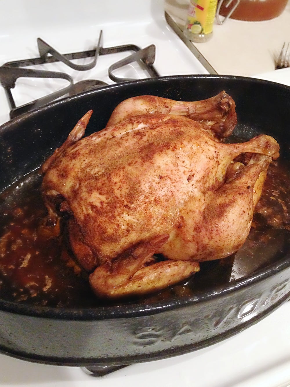 Cooked rotisserie style chicken in roasting pan with juices