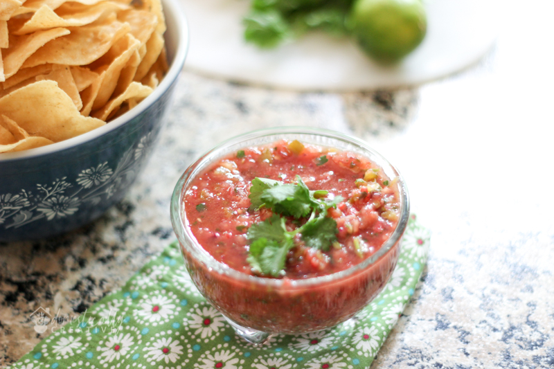 Bowl of homemade salsa topped with cilantro leaves, and tortilla chips