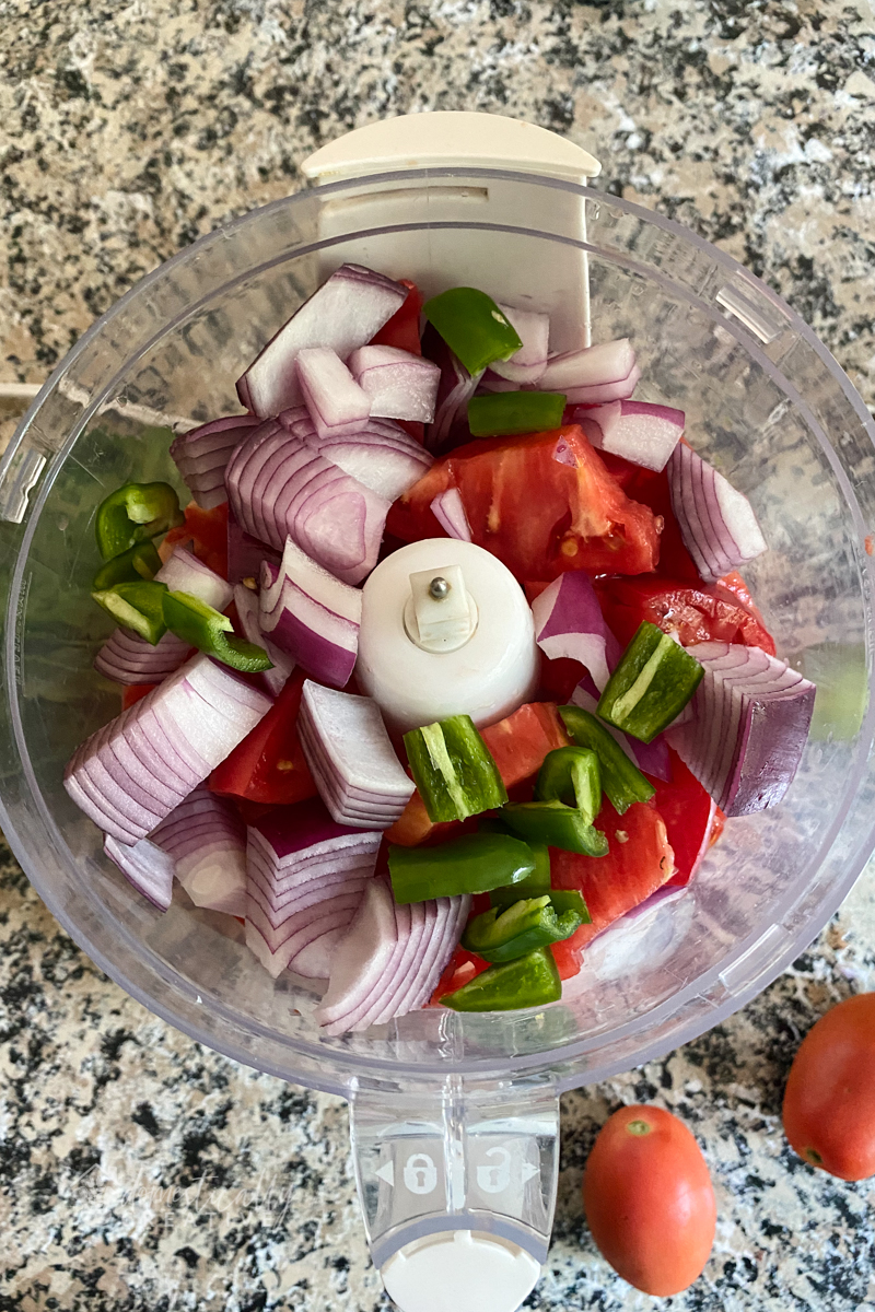 roughly chopped tomatoes, jalapenos, red onion in the bowl of a food processor.