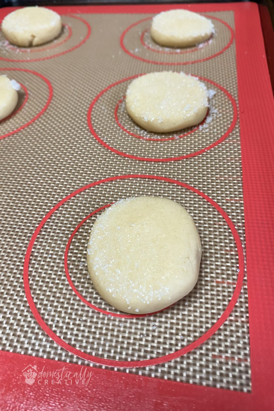 lightly flattened sugar cookie dough balls with sugar on top