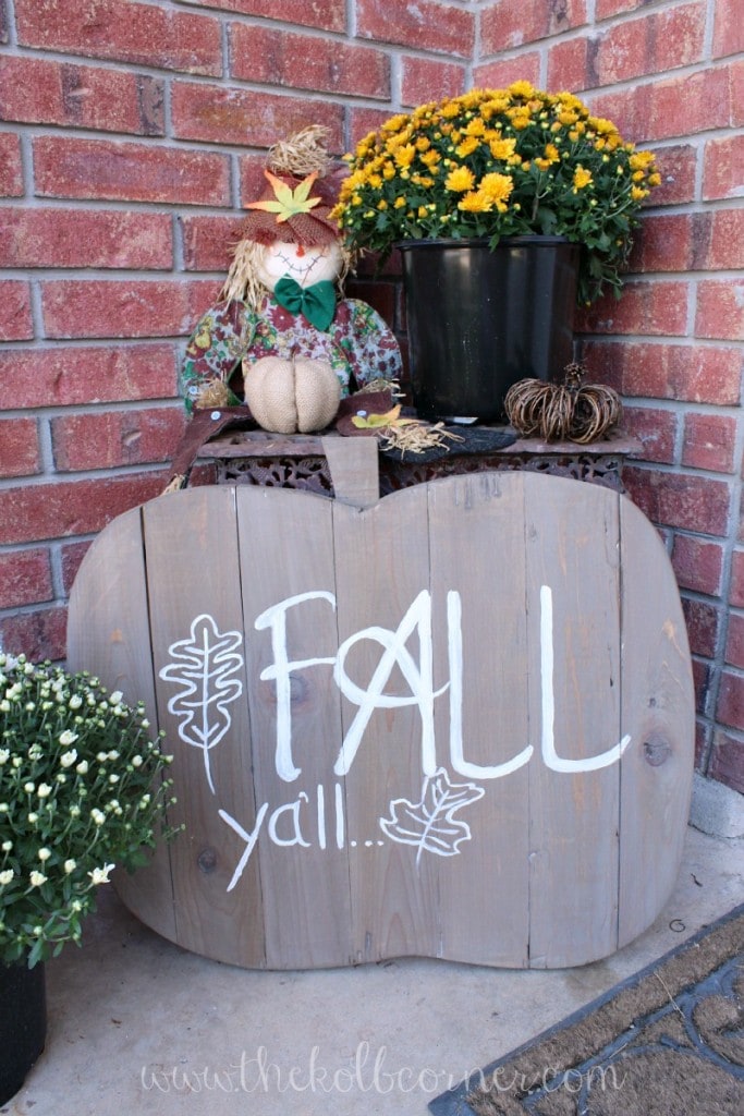 Finished wooden pumpkin sign that says "fall ya'll" set up on front porch