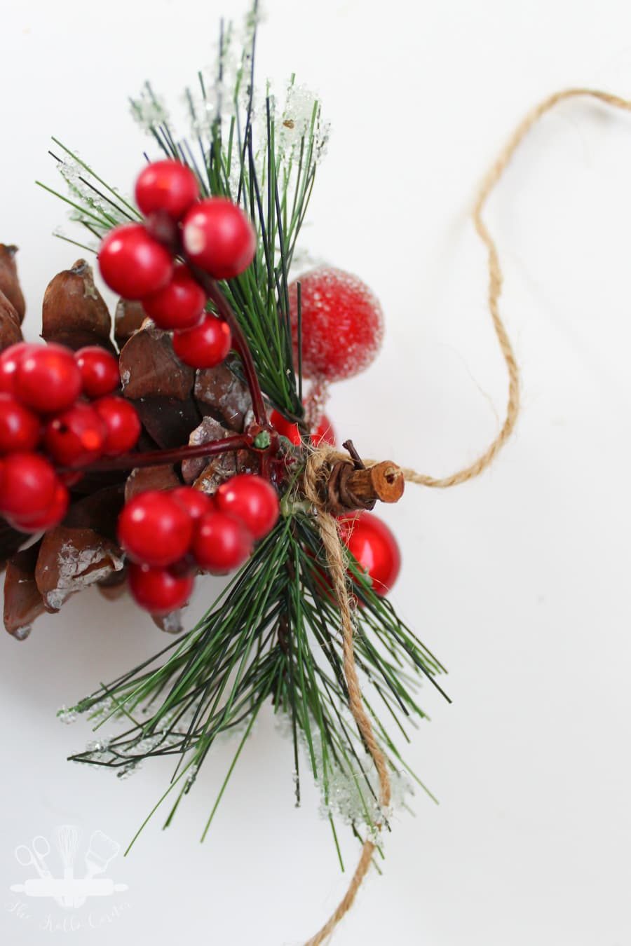 close up of tying twine around the pine cone stem