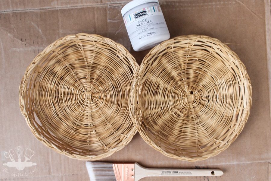 Plain wicker plate chargers with paintbrush and white chalk paint container.