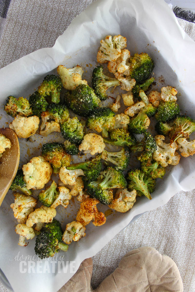 roasted broccoli and cauliflower on sheet pan with wooden spoon and oven mit