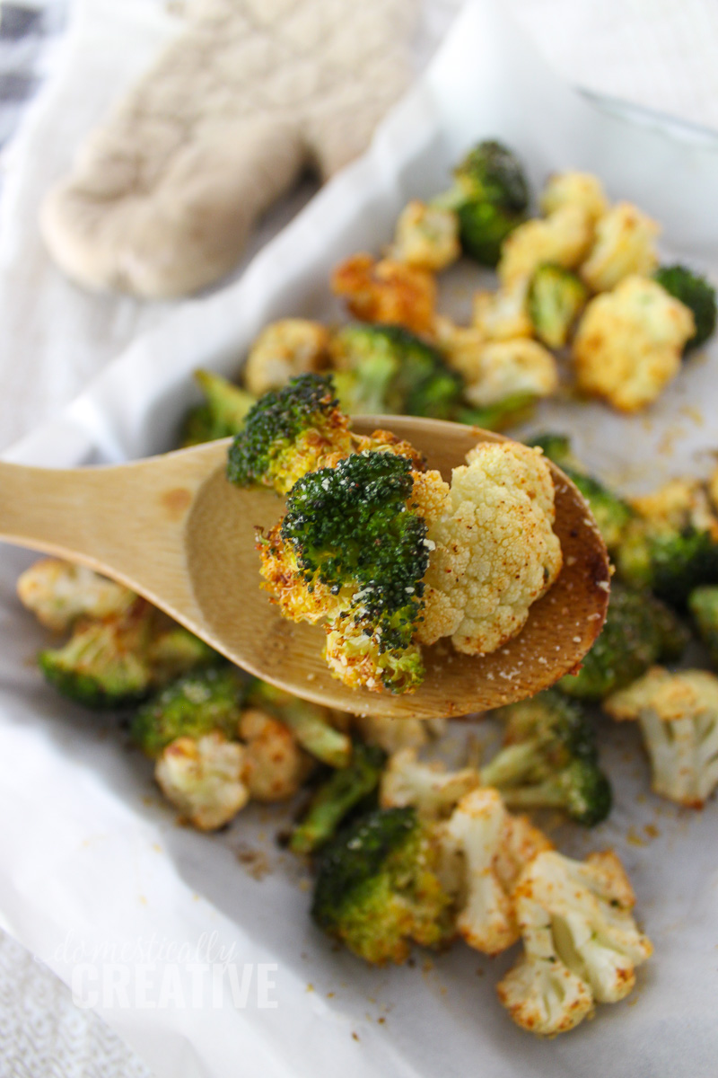 close up of roasted broccoli and cauliflower on a wooden spoon