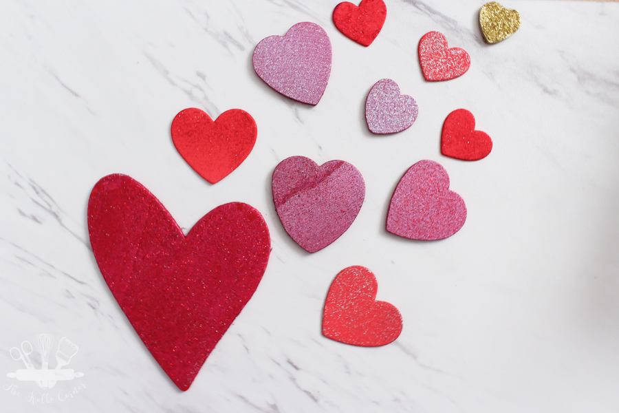 painted red and pink wooden hearts in various sizes on a marble background.