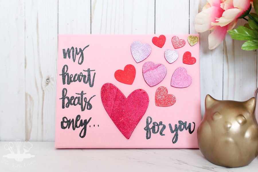finished pink canvas with "My heart beats only for you" hand lettering with various red wooden hearts. With gold owl and pink vase of flowers.