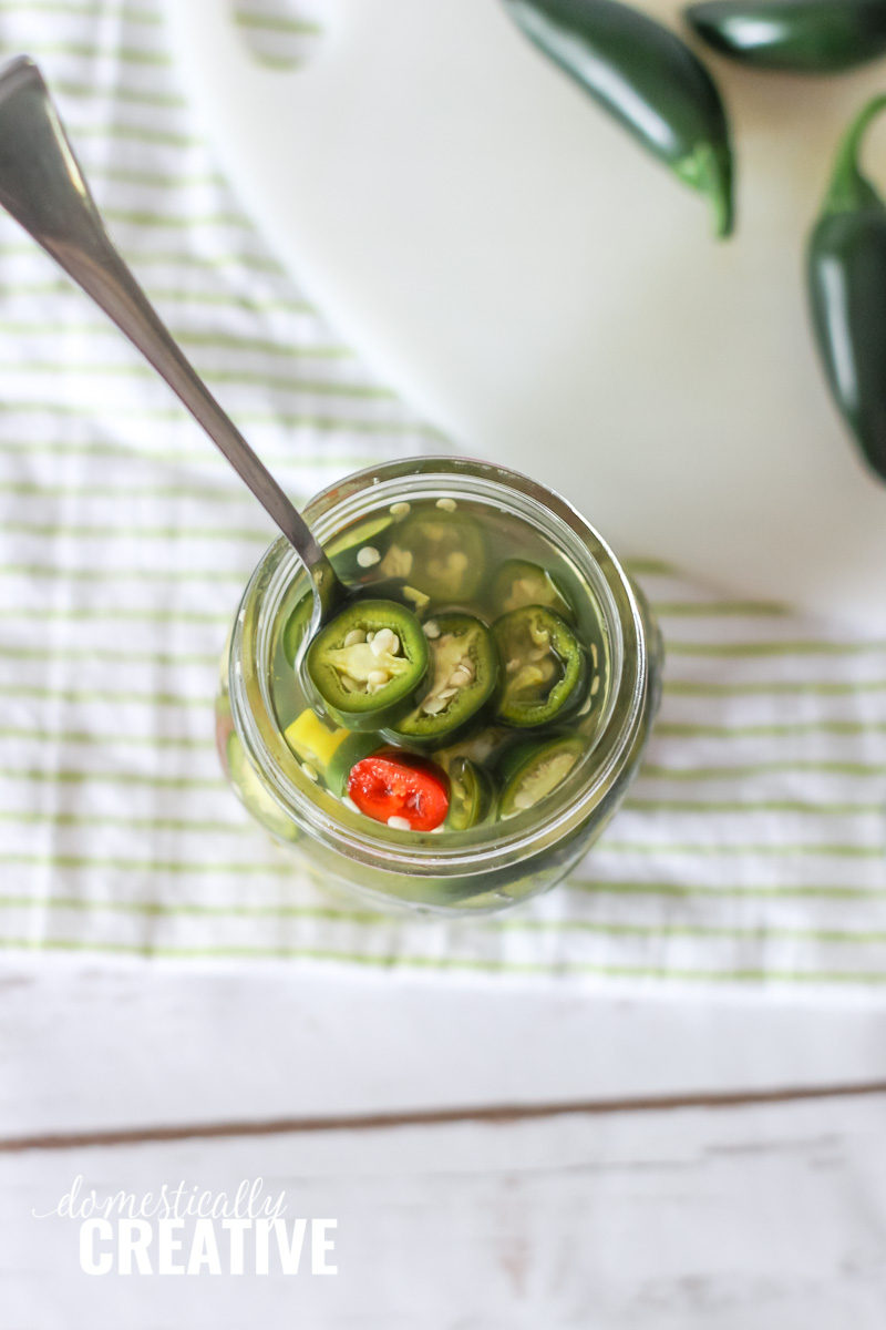 Overhead view of pickled jalapenos in a jar with fork