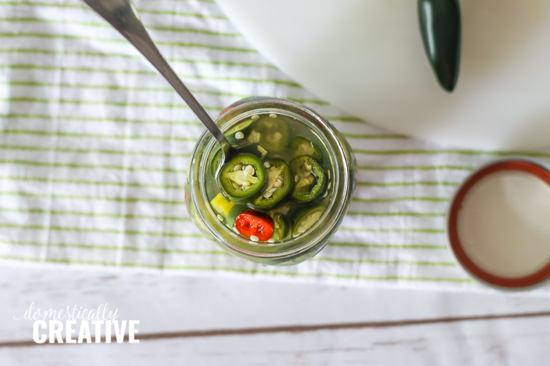 Overhead view of pickled jalapenos in a jar with fork