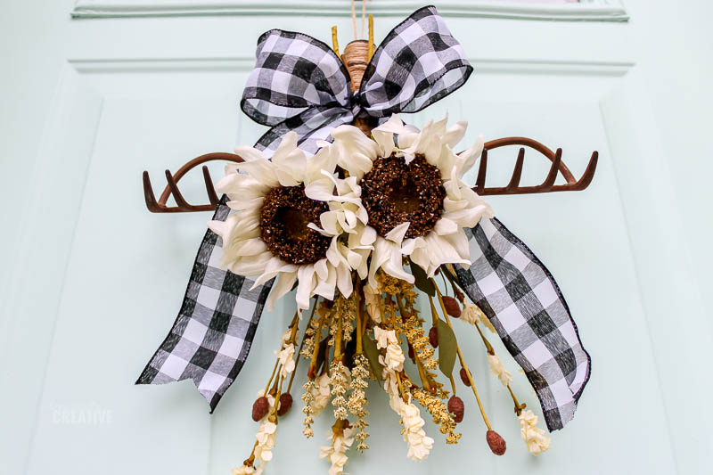 view of rake wreath with sunflowers hanging on front door from below