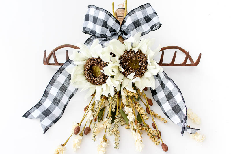 finished rake head wreath with sunflowers and other fall flowers and buffalo check ribbon