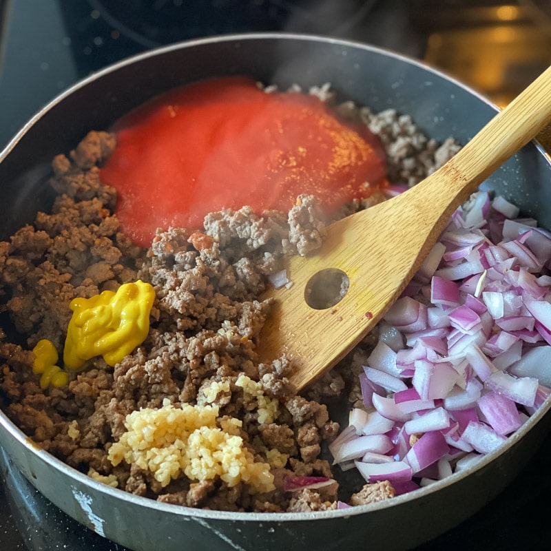 Add onion, garlic, tomato sauce and mustard to ground beef