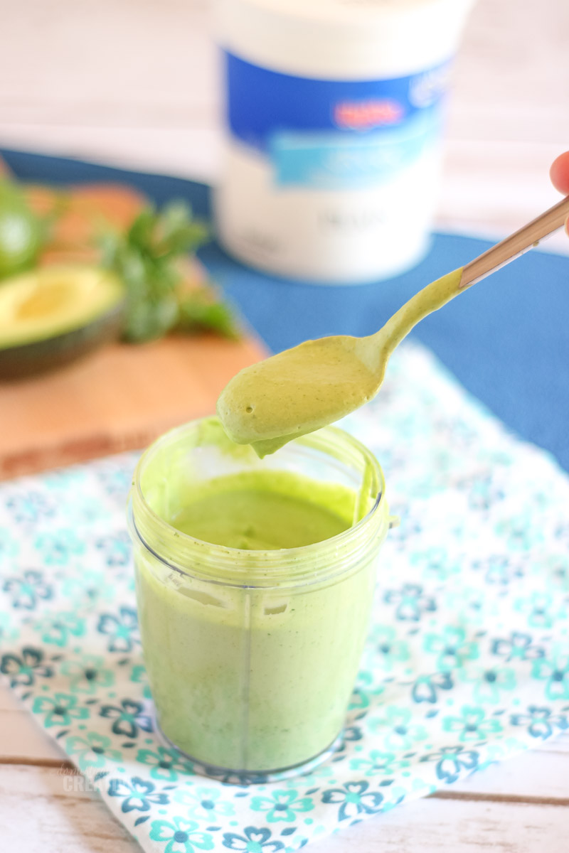 creamy thick dressing in blender jar with spoon, dripping dressing to show thickness