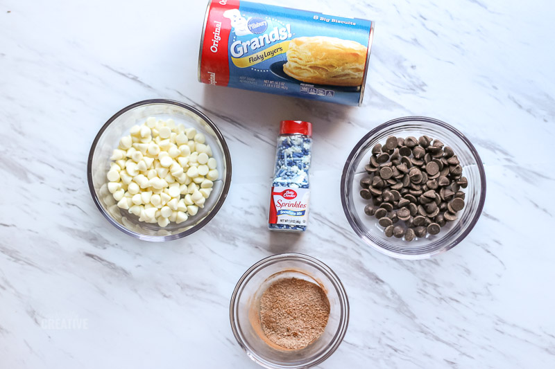 Overhead of donut bite ingredients-biscuit dough, sprinkles, chocolate chips and cinnamon sugar