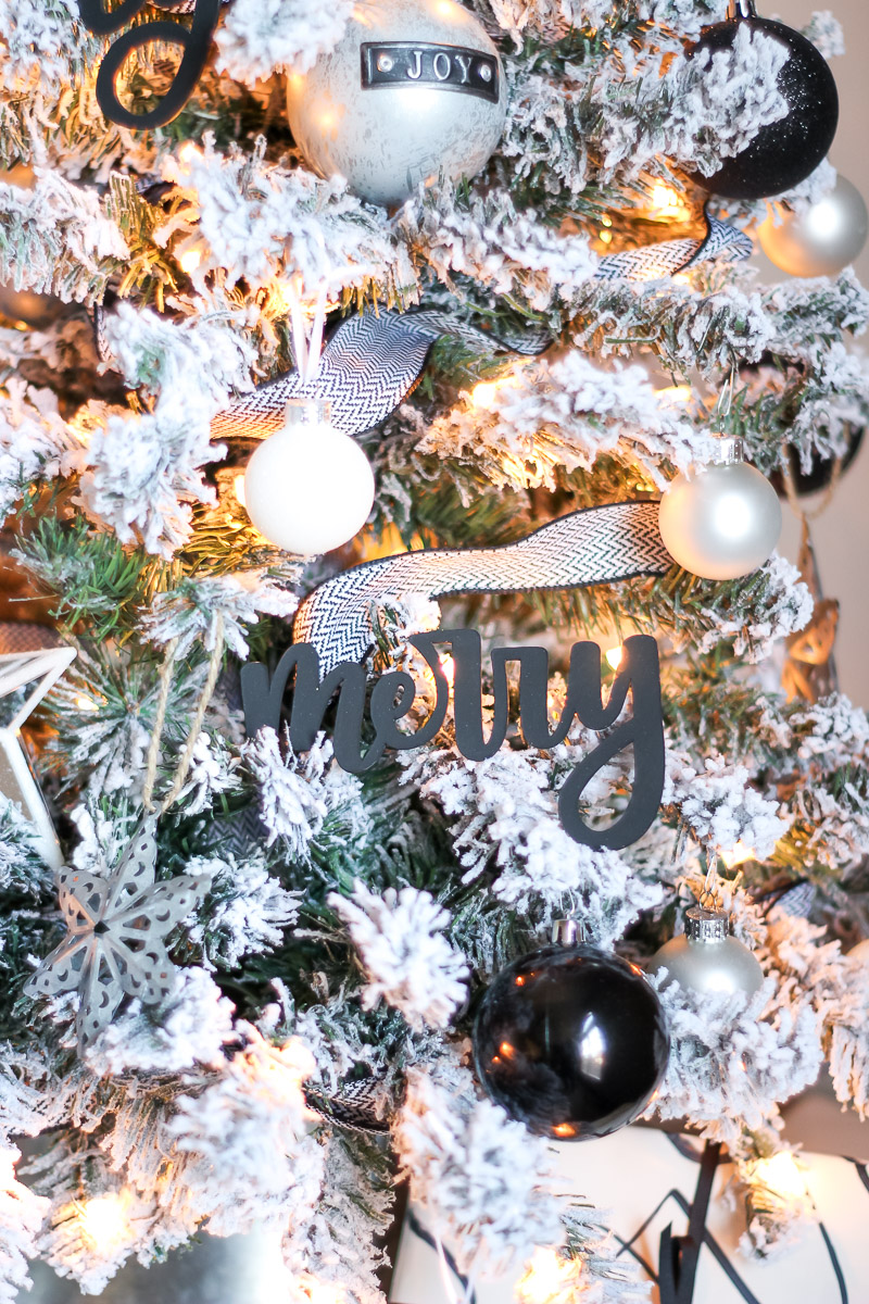 Black hand lettered ornaments close up "Merry" on flocked black and white Christmas tree