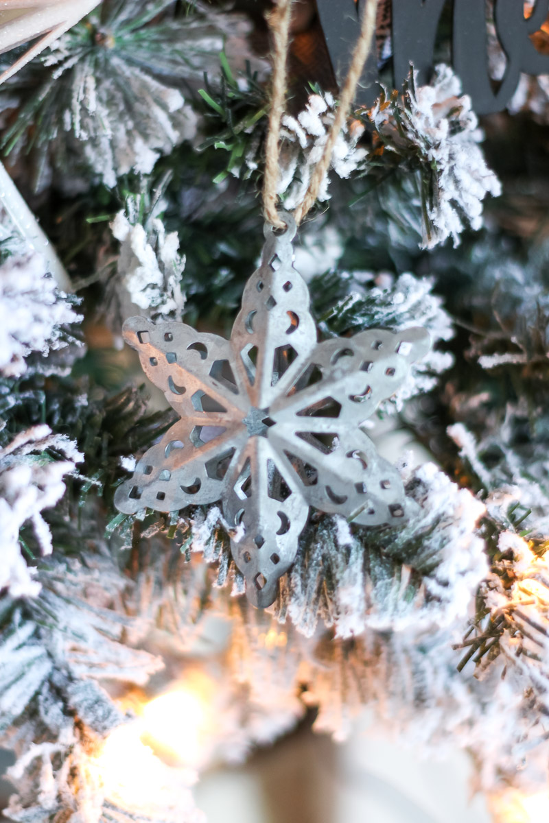 Galvanized metal snowflake ornament close up on flocked Christmas tree