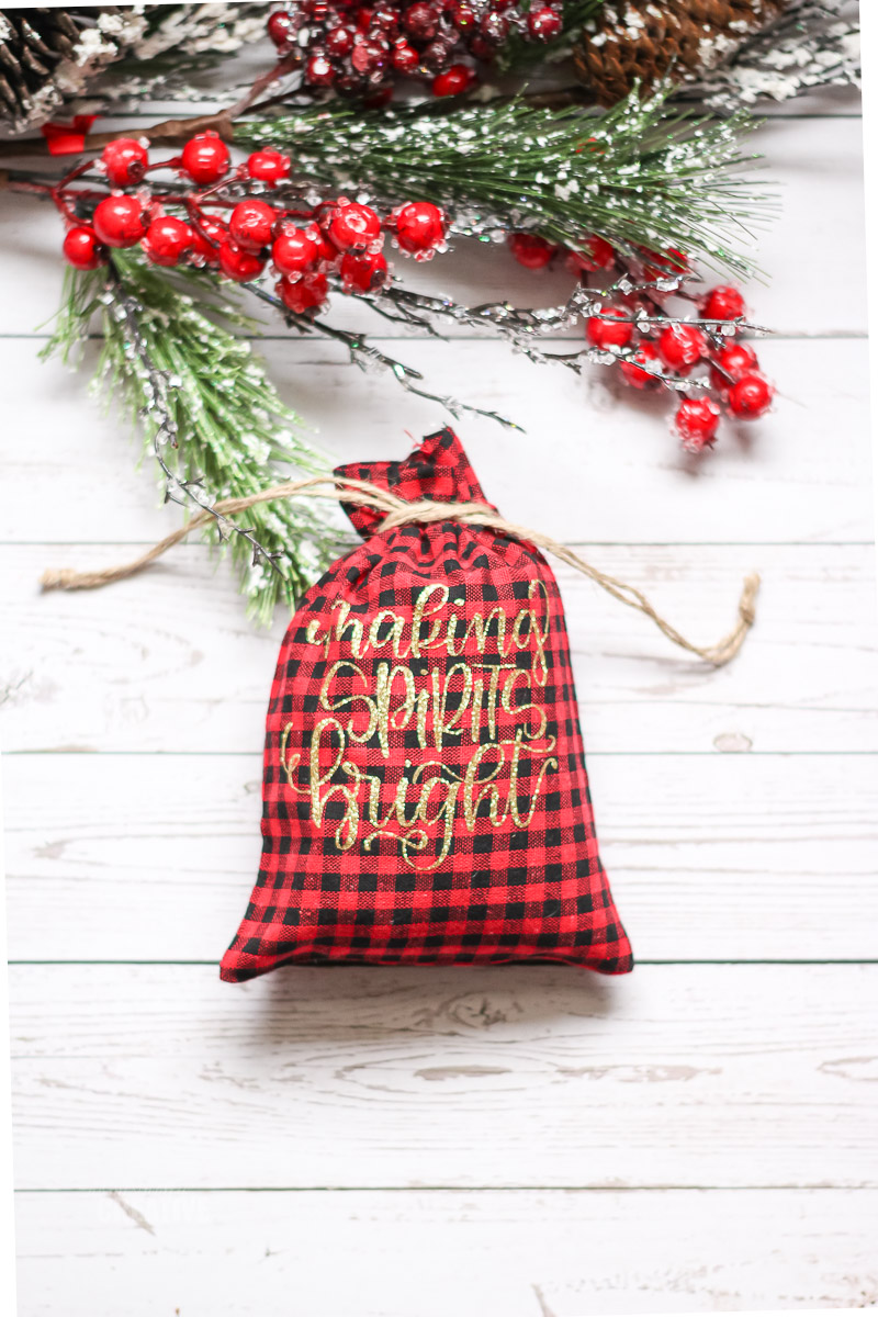 making spirits bright red buffalo check drawstring bag on white wood backdrop