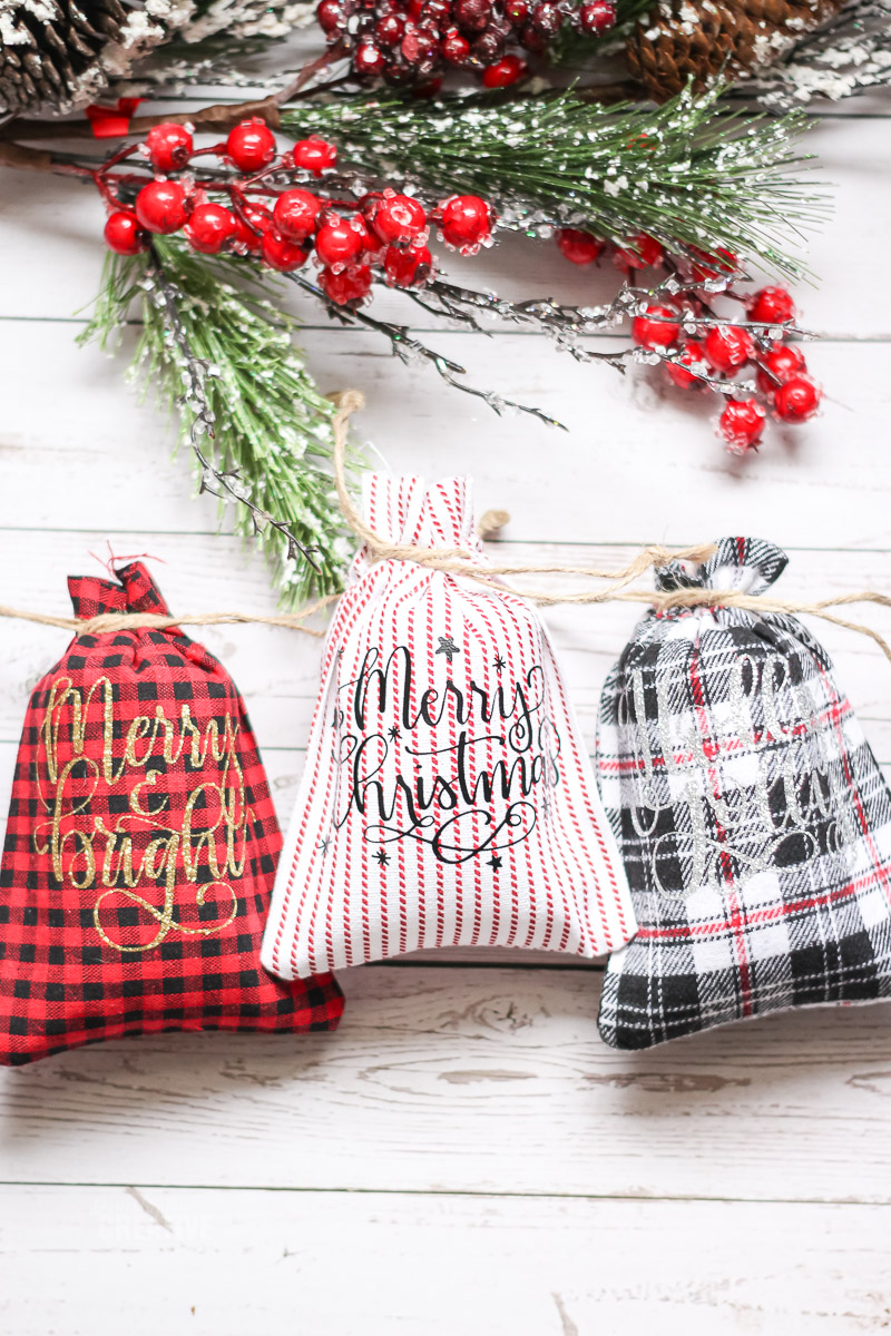 close up overhead of three drawstring Christmas patterned bags on white wood surface