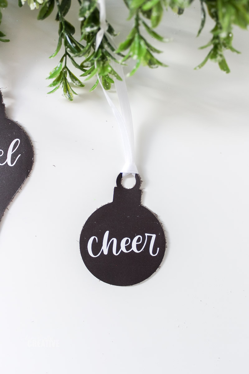 Cheer Leather ornament on white table with greenery