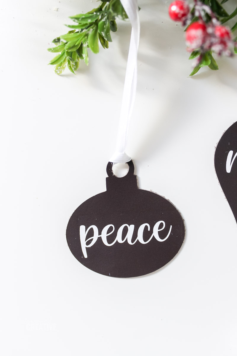 Peace Leather ornament on white table with greenery