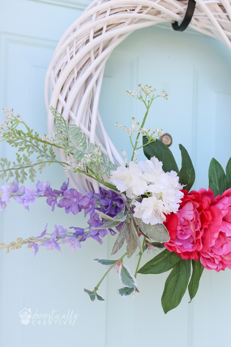 close up of flowers on spring wreath with pale blue door