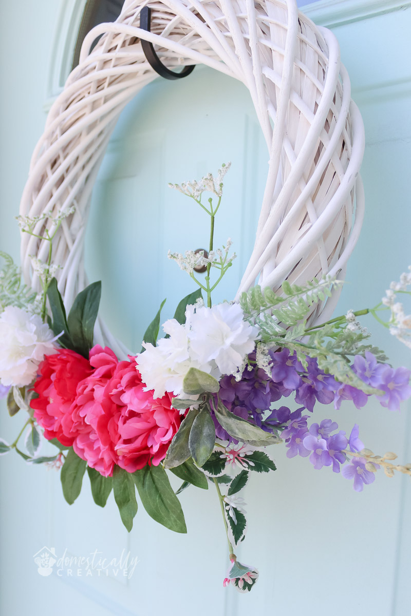 close up of flowers on spring wreath with pale blue door