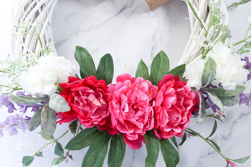 finished florals attached to white wicker wreath form on marble background