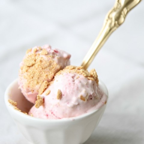 strawberry ice cream in a white bowl with gold spoon